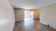 Located at 566 Naples, Unit #153 in Chula Vista, this single-floor residence offers a clean, well-maintained interior with a neutral color palette and practical layout. The main living area is open and airy, featuring warm wood-style laminate flooring, crisp white baseboards, and a textured ceiling. A ceiling fan provides overhead comfort, while a full-width sliding glass door with vertical blinds fills the space with natural light and provides access to the outdoors. The kitchen is efficiently designed with white cabinetry, neutral stone-tone countertops, a stainless steel sink, and includes a refrigerator and stovetop range. The cabinetry offers ample storage throughout. The bathroom features a vanity with white cabinetry, a stone-tone countertop, and a wall-mounted medicine cabinet with mirror. An adjacent closet area with wood-style flooring provides convenient access. The bedroom includes a generously sized walk-in closet with dual-level shelving rods and carpeted flooring, offering practical and organized storage. Overall, the unit presents a tidy, move-in-ready environment with consistent finishes throughout, making it a functional and comfortable living space in Chula Vista.