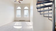 Located at 500 Tripoli Street in Pittsburgh's North Shore area, this two-story, one-bedroom, one-bathroom home offers a well-organized layout spread across two floors. The main level is generously sized, featuring a kitchen equipped with warm wood cabinetry, stone-look countertops, tile flooring, stainless steel appliances including a refrigerator, range, microwave, and dishwasher, plus track lighting above an arched window that frames city skyline views. A distinctive open-riser spiral staircase connects the two levels, serving as both a functional and architectural focal point throughout the space. The living area on the main floor is bright and open, with arched transom windows, a ceiling fan, plush carpeting, and a baseboard heating system. A den provides additional flexible living space. Upstairs, the carpeted hallway leads to the spacious primary bedroom, which benefits from natural light through vertical-blind-fitted windows. Five closets throughout the home offer exceptional storage, including mirrored sliding-door closets in the bedroom area. The full bathroom features hardwood-style flooring, a soaking tub with shower, and clean white finishes. The home's neutral palette and abundant natural light create a bright, welcoming atmosphere throughout.