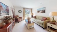 Located at 2000 Varsity Ln in Bear, Delaware, this well-appointed single-floor residence offers a thoughtfully designed layout across a comfortable and cohesive living space. The living room serves as the heart of the home, featuring plush carpeting, crown molding, and a sliding glass door that opens to a private balcony with outdoor views, allowing natural light to fill the room. An adjacent sitting or media area provides additional flexible living space. The dining room is defined by elegant crown molding, a decorative chandelier, and warm neutral tones, creating an inviting setting for meals and entertaining. The kitchen is equipped with light wood cabinetry, laminate countertops, a full suite of appliances including an electric range, and tile flooring that adds practicality and easy maintenance. The primary bedroom is generously sized with plush carpeting, a ceiling fan, a closet, and access to a dual-sink bathroom featuring tile floors, a large vanity mirror, and a tub-shower combination. A second bedroom offers ample natural light through a large window and soft carpeting. A dedicated in-unit laundry area houses a full-size washer and dryer with overhead shelving for added storage. Throughout, the residence maintains a clean, neutral palette with consistent finishes that create a calm, welcoming atmosphere.