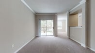 This single-floor residence offers a thoughtfully designed layout that balances comfort and functionality throughout. The main living area is finished with plush wall-to-wall carpeting, neutral warm-toned walls, and elegant crown molding, creating a welcoming atmosphere. A sliding glass door opens to a private outdoor area, allowing natural light to pour in and offering views of mature trees. Crown molding and textured ceilings add a refined architectural touch to the living space, which flows openly into an adjacent room.

The kitchen is well-equipped with rich dark wood cabinetry, dark granite countertops, a stainless steel sink, and black appliances, all set atop warm hardwood-style flooring that extends through the utility areas. A dedicated laundry room with full-size washer and dryer hookups provides added convenience.

The bedrooms are generously sized with soft carpeting, ample natural light from large windows with views of surrounding greenery, and ceiling fans for comfort. The bathrooms feature dark wood vanities with dual sinks, white countertops, large mirrors, and hardwood-style flooring. A carpeted staircase with a polished wood handrail connects levels within the building. Overall, the space presents a clean, neutral palette suited for a variety of living styles.