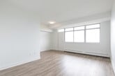 Located at 1 Rosemount Dr in Toronto's Scarborough area, this 1-bedroom, 1-bathroom unit offers a clean, modern aesthetic with a thoughtfully organized layout across a single floor. Light wood-look flooring runs throughout the space, complementing the crisp white walls and creating a bright, cohesive feel.

The open living area is a standout feature, highlighted by a wide bank of floor-to-ceiling windows that flood the room with natural light and offer sweeping views of the surrounding cityscape. A baseboard heating system runs along the window wall, ensuring year-round comfort.

The kitchen is efficiently designed in a galley style, featuring white shaker cabinetry extending to the ceiling for ample storage, a grey countertop with a double stainless steel sink, white subway tile backsplash, and stainless steel appliances including a refrigerator, electric range, and over-the-range microwave.

The bedroom is a comfortable, well-proportioned room with its own window offering city views, baseboard heating, and a set of sliding panel closet doors providing generous storage. The full bathroom is finished in a clean, contemporary style with white subway tile surrounding the shower-tub combo, a single vanity with white cabinetry, and a large mirror. A hallway connects all areas of the unit, completing this practical and attractive urban residence.