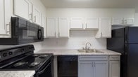 Located at 7716 Sunrise Cir in Birmingham, Alabama, this single-floor residence offers a clean, updated interior with a cohesive modern design throughout. The kitchen is a standout feature, showcasing crisp white upper shaker-style cabinetry paired with contrasting gray lower cabinets, granite-look countertops, a subway tile backsplash, and a full suite of black appliances including an electric range, built-in microwave, and dishwasher. A double-basin stainless steel sink completes the functional layout. Light wood-style flooring runs throughout the main living and bedroom areas, lending warmth and continuity to the space. The living area is generously proportioned, benefiting from multiple windows and a sliding glass door that floods the room with natural light. The bedrooms are well-sized, each featuring the same wood-style flooring, neutral walls, and window blinds; one room includes a ceiling fan with light fixture for added comfort. The bathroom is neatly appointed with a gray vanity, granite-look countertop, a large mirror, and a full tub-shower combination, all finished with wood-style flooring. Textured ceilings are consistent throughout the home. The overall ambiance is bright, clean, and move-in ready, reflecting a thoughtfully refreshed interior.