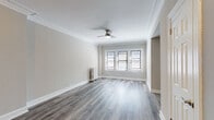 Located on West Fullerton Parkway in Chicago's desirable Lincoln Park neighborhood, this thoughtfully renovated single-floor residence blends classic architectural details with modern updates throughout. Hardwood-style plank flooring flows continuously across all rooms, complemented by crisp white crown molding and baseboards that lend an elegant, traditional character to the space.

The generously proportioned living area features a ceiling fan, ornate crown molding, and a triple window arrangement that draws in abundant natural light. A separate bedroom offers corner windows on two walls, providing cross-ventilation and a bright, airy feel, also equipped with a ceiling fan overhead.

The compact kitchen is efficiently designed with white Shaker-style cabinetry, a stainless steel refrigerator and gas range, and a cool-toned subway tile backsplash that adds a stylish accent. Warm flush-mount lighting and decorative crown molding detail the transition area between the living and kitchen spaces.

The bathroom is a standout feature, showcasing a deep soaking tub with an overhead shower fixture, a sleek gray vanity with modern hardware, wood-look flooring, and a charming cast-iron radiator—a nod to the building's historic character. Built-in shelving provides convenient storage within the bathroom as well. Classic cast-iron radiators are found throughout, further reflecting the home's enduring architectural heritage.