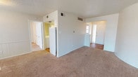 Located at 2310 70th St in Lubbock, Texas, this single-story residence offers a straightforward and functional layout spread across a well-organized floor plan. The living area is generously proportioned, featuring wall-to-wall carpet, a textured ceiling, and a distinctive curved accent wall that adds a subtle architectural touch. Panel-style wainscoting along one wall lends a classic character to the space, while overhead lighting keeps the area bright and welcoming.

The kitchen is positioned centrally within the home, featuring white cabinetry and a full-size refrigerator, with easy access to the main living areas. An adjacent galley-style utility space provides dual countertops with white cabinetry on both sides, offering ample storage and workspace.

The bedrooms are comfortably sized, each equipped with ceiling fans with light fixtures and windows fitted with blinds that bring in natural light. One bedroom includes a direct en-suite bathroom connection, enhancing privacy and convenience. Both bathrooms are clean and functional, each featuring a tiled tub-surround combination, a vanity with a countertop sink, a toilet, and wood-look flooring that adds warmth to the space. The overall ambiance of the home is neutral and move-in ready, with a light color palette throughout.