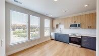 Located at 2902 N Arthur Ashe Blvd in Richmond, VA, this thoughtfully designed one-bedroom, one-bathroom unit offers a modern aesthetic with clean finishes throughout. Light hardwood flooring flows seamlessly from room to room, complementing the crisp white walls and creating a bright, cohesive atmosphere.

The kitchen serves as a functional centerpiece, featuring a two-tone cabinet design with blue-gray lower cabinets accented by gold hardware and natural wood upper cabinetry. A white subway tile backsplash and stainless steel appliances — including a refrigerator, electric range, built-in microwave, and dishwasher — complete the contemporary look. Large windows flood the kitchen and living area with natural light while offering views of the surrounding neighborhood.

The bedroom is a well-proportioned, serene retreat with continued hardwood flooring, a ceiling fan, and a pair of bold charcoal double doors that open to a closet. Additional windows provide outdoor views and further natural light.

The entrance hallway features matte black door accents and recessed lighting, offering a polished first impression. The bathroom is finished with a blue vanity with gold hardware, a white countertop, and a tub-shower combination with white tile surround and matte black fixtures, tying together the unit's consistent design language.