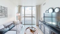 Located at 2500 Edwards Dr in Fort Myers, FL, this thoughtfully designed one-bedroom, two-bathroom residence offers an efficient and elegant layout bathed in natural light. The space features two living areas, both with floor-to-ceiling windows framing sweeping views of the Caloosahatchee River and a nearby bridge, creating a bright, airy atmosphere throughout. Light wood-style flooring flows seamlessly across the unit, complementing the clean, neutral color palette.

The kitchen is outfitted with white shaker cabinetry, granite countertops, white subway tile backsplash, and stainless steel appliances including a dishwasher, microwave, and cooktop. A pantry provides additional storage. The spacious primary bedroom enjoys generous natural light through large windows with water views, and features multiple closets for ample storage. Both bathrooms are finished with granite-topped white vanities and glass-enclosed walk-in tile showers, lending a polished, spa-like quality.

Additional highlights include a dedicated laundry area, a hallway connecting the main spaces, and abundant closet storage throughout. The second living area functions well as a home office or flex space, also offering direct waterway views. The overall ambiance is calm and contemporary, ideal for enjoying Florida's waterfront lifestyle.