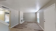 This two-floor residence offers a clean, updated interior with a neutral color palette and a cohesive design throughout. The main living area welcomes you with light-toned luxury vinyl plank flooring and a textured ceiling, creating a bright and open atmosphere. A standout built-in feature wall with integrated shelving adds both character and practical storage to the living space, while a window dressed with blinds allows natural light to filter in.

The kitchen has been thoughtfully updated, showcasing crisp white subway tile backsplash, white cabinetry with modern hardware, light countertops, a double stainless steel sink, and a black electric range with a range hood — combining functionality with a contemporary aesthetic.

The bedrooms are carpeted for comfort and include windows that bring in ample natural light. One room features a sliding glass door with vertical blinds, providing access to an outdoor area. The bathrooms are finished with clean white tilework, including a full tub-and-shower combination, white vanities, and large mirrors.

Additional features include textured walls throughout, consistent neutral gray tones, and a layout that efficiently utilizes the space across both floors. The overall ambiance is fresh, move-in ready, and well-suited for comfortable everyday living.