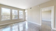 Located in the heart of downtown Houston, this one-bedroom, one-bathroom unit offers a thoughtfully designed layout with contemporary finishes throughout. Polished concrete floors flow seamlessly across the main living areas, reflecting natural light that pours in through large double-hung windows framing views of the surrounding urban skyline. The open living area is bright and airy, with neutral warm-toned walls and a private entry door.

The kitchen is a standout feature, showcasing white shaker cabinetry, a striking marble-veined stone countertop island with a built-in sink and wine storage, pendant lighting, a tile backsplash, and a full suite of stainless steel appliances including a gas range, microwave, and French door refrigerator. The space is well-suited for both everyday cooking and entertaining.

The bedroom offers a comfortable footprint with carpeted flooring, a ceiling fan, and a bank of windows providing ample natural light and city views. A dedicated closet provides convenient storage.

The bathroom is generously proportioned, featuring a dual-sink vanity with white cabinetry, a large wall mirror, brushed nickel fixtures, a soaking tub, and polished concrete flooring that maintains the modern aesthetic found throughout the unit.