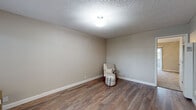 Located in Lafayette, CA (94549), this single-floor unit offers a practical and well-appointed layout across several distinct areas. The living area welcomes you with warm wood-look vinyl flooring, neutral warm-gray walls, a textured ceiling, and a window that allows natural light and views of surrounding greenery. A ceiling fan and wall-unit HVAC provide year-round comfort. The space flows into a secondary room, also with wood-look flooring and a ceiling fan, ideal for a home office or flex space. The galley-style kitchen is efficiently designed, featuring rich dark-wood cabinetry, light quartz countertops, a stainless steel sink, and a full suite of stainless appliances including a refrigerator, electric range, and microwave. Light hardwood-tone flooring carries through the kitchen. The bedroom is carpeted for comfort and includes a ceiling fan, textured ceiling, and ample wall space. A built-in desk area with dark cabinetry adds a functional touch near the hallway. The bathroom is clean and simply appointed with white fixtures, quartz countertop vanity, chrome towel rack, and smooth white walls. The 3D floorplan reveals a cohesive, compact, and well-organized layout suited for efficient everyday living.