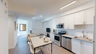 Located on the iconic West Sunset Boulevard in Los Angeles, this thoughtfully designed studio offers a single-floor open-concept layout that efficiently combines the kitchen, dining, and living areas into one cohesive space. Light wood-style flooring runs throughout, complementing the clean, bright white walls and recessed and linear LED lighting that keep the interior well-lit and inviting.

The fully equipped kitchen is a standout feature, showcasing white shaker-style cabinetry with modern hardware, white subway tile backsplash, light quartz countertops, and a full suite of stainless steel appliances including an electric range, over-the-range microwave, dishwasher, and full-size refrigerator. A dining area with a marble-top table and seating flows naturally into the living space, which offers room for a sofa and entertainment setup, with windows providing natural light and views of the surrounding neighborhood.

The bathroom continues the clean, contemporary aesthetic with white cabinetry, a single-sink vanity with a framed mirror, wood-style flooring, and a full shower-tub combination. The overall design is cohesive and modern, making this compact yet functional space well-suited for urban living in the heart of Hollywood.