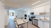 Located on the iconic West Sunset Boulevard in Los Angeles, this thoughtfully designed studio offers a single-floor open-concept layout that efficiently combines the kitchen, dining, and living areas into one cohesive space. Light wood-style flooring runs throughout, complementing the clean, bright white walls and recessed and linear LED lighting that keep the interior well-lit and inviting.

The fully equipped kitchen is a standout feature, showcasing white shaker-style cabinetry with modern hardware, white subway tile backsplash, light quartz countertops, and a full suite of stainless steel appliances including an electric range, over-the-range microwave, dishwasher, and full-size refrigerator. A dining area with a marble-top table and seating flows naturally into the living space, which offers room for a sofa and entertainment setup, with windows providing natural light and views of the surrounding neighborhood.

The bathroom continues the clean, contemporary aesthetic with white cabinetry, a single-sink vanity with a framed mirror, wood-style flooring, and a full shower-tub combination. The overall design is cohesive and modern, making this compact yet functional space well-suited for urban living in the heart of Hollywood.