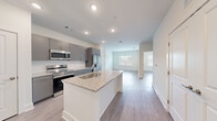 This thoughtfully designed 1-bedroom, 1-bathroom residence offers a cohesive open-concept floor plan that maximizes every square foot. The kitchen serves as the centerpiece of the living area, anchored by a central island with a granite countertop and undermount sink. Sleek gray cabinetry, a subway tile backsplash, and a full suite of stainless steel appliances — including a refrigerator with ice maker, range, and over-the-range microwave — give the kitchen a clean, contemporary feel. Light wood-tone flooring runs throughout the space, tying the rooms together seamlessly.

The living room extends naturally from the kitchen, bathed in natural light from large windows with views to the outdoors. A ceiling fan adds both function and a finishing touch to the space. The bedroom is a comfortable, light-filled retreat with its own window and direct access to a walk-in closet equipped with wire shelving on multiple walls for generous storage.

The bathroom features a gray vanity with a granite countertop, an undermount sink, a large mirror, and a tiled shower-tub combination. Neutral walls and wood-look flooring maintain the home's consistent modern aesthetic. Recessed lighting throughout ensures a bright, welcoming ambiance in every room.