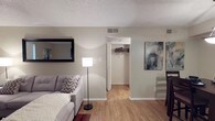 This single-floor residence offers a thoughtfully arranged layout that balances comfort and functionality across its key living areas. The living room features warm hardwood-style flooring, a sliding glass door that fills the space with natural light, and a textured ceiling. A conveniently located closet provides ample storage just off the main living area. Adjacent to the living room, the dining area is defined by a stylish pendant light overhead, creating an inviting space for meals and gatherings. The galley-style kitchen is efficiently designed with warm wood cabinetry lining both sides, dark countertops, black appliances including a range and refrigerator, and a utility area visible through a pass-through doorway. The multiple bedrooms are carpeted and offer a quiet, cozy atmosphere, each with windows that allow natural light to filter in. The primary bedroom connects directly to a full bathroom featuring warm wood vanity cabinetry, a large mirror, granite-style countertops, and a shower-tub combination. A second full bathroom mirrors this functional design with its own vanity and shower. Throughout the space, textured ceilings, neutral wall tones, and consistent hardwood-style or carpeted flooring tie the rooms together cohesively.