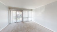 Located at 2905 Clairemont in San Diego, this single-story unit offers a practical and comfortable layout with a variety of functional spaces throughout. The floor plan, visible in the 3D model, reveals a well-organized arrangement of living, sleeping, kitchen, and bathroom areas connected by a central corridor.

The living area is bright and spacious, featuring neutral carpet flooring, a ceiling fan with integrated lighting, and a wall of vertical blinds covering sliding glass doors that open to an outdoor view of a pool area. A decorative shiplap-style accent wall adds a subtle design element to the room.

The kitchen is outfitted with rich, dark wood cabinetry, granite-style countertops, tile flooring, a double-basin sink, gas range, dishwasher, and a full-size refrigerator. A window above the sink provides natural light and ventilation.

The bedrooms continue the carpeted flooring and neutral color palette. One bedroom features a ceiling fan, a window with vertical blinds, and a shiplap accent wall. Another bedroom includes a louvered closet door, crown molding, and direct access to the hallway.

The bathroom is finished with tile flooring, a wood vanity with granite-style countertop, a large mirror, and a tub-shower combination enclosed by sliding glass doors.