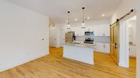 Located at 803 Holliday Dr in Greensboro, NC, this thoughtfully designed 2-bedroom, 2-bathroom residence offers a clean, modern aesthetic across a single floor. Light hardwood-style flooring flows consistently throughout, creating a bright and cohesive feel in every room. The open-concept kitchen serves as the centerpiece of the home, featuring white shaker cabinetry extending to the ceiling, granite countertops, stainless steel appliances, a central island with pendant lighting, recessed lighting, and a distinctive sliding barn door — a standout design element that adds rustic character. Both bedrooms are well-proportioned, with the primary bedroom offering a walk-in closet and direct access to the rest of the home. The second bedroom benefits from multiple windows that invite generous natural light and outdoor greenery views, complemented by a ceiling fan. The two bathrooms are finished with white cabinetry, granite countertops, and light wood flooring — one featuring a walk-in shower with brushed nickel fixtures. A hallway and closet round out the functional layout. Throughout, the white walls, clean lines, and consistent finishes create a bright, inviting ambiance well-suited for comfortable everyday living.
