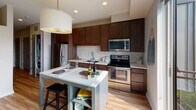 Located at 1300 W Lake St in the vibrant Uptown neighborhood of Minneapolis, this single-floor residence offers a well-designed layout with modern finishes throughout. A welcoming hallway with light wood-style flooring connects the living spaces, flanked by a sliding barn-style door that adds a contemporary touch. The hallway leads to a bright, open living and dining area filled with natural light from large windows. The kitchen is a standout feature, equipped with rich dark-stained wood cabinetry, stainless steel appliances including a refrigerator, electric range, microwave, and dishwasher, along with a crisp white subway tile backsplash and light countertops. A compact kitchen island with built-in shelving provides additional prep and dining space, complemented by a pendant drum light overhead. The bedroom offers a cozy retreat with warm ambient lighting, a ceiling fan, and tasteful décor. The full bathroom is finished with clean white tile surrounding a full tub-shower combination, dark tile flooring, a wood-framed vanity mirror, and a single-sink vanity. Recessed lighting throughout the unit ensures consistent illumination, while the overall design reflects a cohesive, contemporary aesthetic suited for urban living.