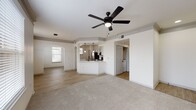 This contemporary apartment showcases an open floor plan that seamlessly integrates living spaces. The interior boasts a harmonious mix of plush carpeting and sleek wood flooring, creating distinct zones within the home. Large windows flood the rooms with natural light, while modern ceiling fans ensure comfort. The kitchen is a highlight, featuring white cabinetry, stainless steel appliances, and a stylish herringbone backsplash. Architectural elements like arched doorways and a circular light fixture add visual interest. The bathroom continues the modern aesthetic with clean lines and bright lighting. Overall, the space offers a fresh, airy ambiance suitable for comfortable living.