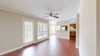 This single-story, 3-bedroom, 2-bathroom home offers a thoughtfully designed layout that maximizes functionality across its well-utilized floor plan. The open-concept living, dining, and kitchen area serves as the heart of the home, featuring rich hardwood-style flooring, crown molding, and a ceiling fan with light fixture. Large windows with white plantation-style blinds flood the space with natural light, while a patio door provides direct access to the outdoor patio area.

The kitchen is equipped with warm wood cabinetry, granite-style countertops, stainless steel refrigerator, black appliances including a built-in oven and microwave, and a peninsula with a sink — ideal for both cooking and casual dining. A pantry offers additional storage convenience.

The bedrooms are carpeted and finished with neutral tones, crown molding, and ceiling fans, creating comfortable, quiet retreats. The primary bedroom provides a generous footprint with a dedicated closet. The two bathrooms feature wood-toned vanities with stone-look countertops and tiled tub-shower combinations with classic white subway tile accented by diagonal stone tile at the top border. Additional highlights include four closets, a dedicated laundry area, and a hallway connecting the living spaces efficiently throughout the home.