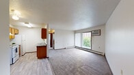 Located at 123 E 59th St in Minneapolis, MN, this single-floor unit offers a practical and functional layout suited for everyday living. The open living area is generously sized, finished with neutral carpet and a textured ceiling, and receives natural light through a large sliding glass door that opens onto a private balcony overlooking greenery. A wall-mounted air conditioning unit and baseboard heating provide year-round climate control.

The galley-style kitchen is efficiently designed, featuring warm wood cabinetry, dark granite-style countertops, a double sink, and white appliances including a range and refrigerator. Light wood-style flooring runs throughout the kitchen, contrasting with the carpeted living and sleeping areas.

The bedrooms are well-proportioned, each carpeted and equipped with closets offering built-in hanging rods. One bedroom includes a window with views of surrounding trees, while another connects to the balcony via a sliding glass door. Baseboard heaters are present throughout.

The full bathroom includes a tiled tub-shower combination, a vanity with storage, and tile flooring. The entry area transitions between wood-style and carpeted flooring, providing a clean delineation between spaces. Overall, the unit offers a straightforward, comfortable living environment in a residential Minneapolis neighborhood.