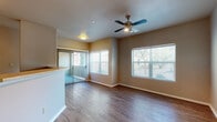 Located at 1325 Northwestern Dr in El Paso, Texas, this single-floor residence offers a well-designed layout with consistent finishes throughout. The living area is bright and open, featuring rich wood-look flooring, neutral-toned walls, and a ceiling fan with integrated lighting. Large windows dressed with horizontal blinds invite abundant natural light and provide outdoor views, while a sliding glass door with vertical blinds extends the space toward the exterior. A raised counter bar separates the living area from the kitchen, which is equipped with rich dark wood cabinetry, light countertops, tile flooring, and stainless steel appliances including a gas range, over-the-range microwave, and refrigerator. The bedrooms continue the wood-look flooring theme, each featuring ceiling fans and windows that allow for natural light and ventilation. The bathroom is finished with large-format tile flooring, a dark wood vanity with an integrated sink, a wall-mounted mirror, and access to a hallway closet. Clean white baseboards and trim provide a crisp contrast throughout the home, contributing to an overall cohesive and well-maintained aesthetic across every room.
