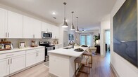 Located at 6026 Station Crossing Ave in Charlotte, NC, this thoughtfully designed one-bedroom, one-bathroom residence offers a bright and functional open-concept floor plan. Light wood-tone flooring flows throughout, unifying the living, dining, and kitchen areas into a cohesive, airy space.

The kitchen is a standout feature, showcasing crisp white shaker cabinetry, quartz countertops, a subway tile backsplash, and a full suite of stainless steel appliances including a refrigerator, electric range, and microwave. A central island with an undermount sink and seating provides additional prep space and a casual dining option, while stylish pendant lighting adds a modern touch overhead.

The living room is bright and welcoming, with large windows and a glass-paneled door that invite natural light. A ceiling fan adds comfort, and the open sightlines to the kitchen make the space feel expansive.

The bedroom is a calm retreat, featuring a large window, ceiling fan, and a dedicated closet. The full bathroom is well-appointed with a white vanity, quartz countertop, and a soaking tub with floor-to-ceiling tile surround. Light-toned flooring continues here, maintaining a clean, cohesive aesthetic throughout this efficiently designed Charlotte residence.