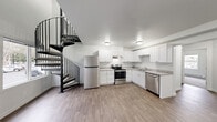 La Madera 3x2 is a well-appointed two-story residence located in Federal Way, WA, offering three bedrooms and two full bathrooms across a thoughtfully distributed floor plan. The main level provides the larger share of the living space and serves as the functional heart of the home. The kitchen is a standout feature, showcasing crisp white shaker cabinetry, light-toned countertops, and a full suite of stainless steel appliances including a refrigerator, electric range, and dishwasher. Wood-look plank flooring runs throughout the main level, lending a clean, modern aesthetic. A striking spiral staircase connects the two floors, adding an architectural focal point to the open main level. Adjacent to the kitchen, the living area offers an open, airy feel with neutral walls and ample room to personalize. The upper level houses the bedrooms, each carpeted for comfort and featuring closets for storage. The generously sized primary bedroom benefits from natural light through large windows with neighborhood views. Both bathrooms are finished in a clean, all-white palette with tub/shower combinations and wood-look flooring. The hallway and dedicated closet space on the upper level further enhance the home's practical layout, making this a functional and move-in-ready residence.