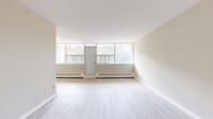 Located at 544 Birchmount Road in Toronto's Scarborough neighbourhood, this one-bedroom, one-bathroom unit offers a functional and well-laid-out living space across a single floor. Light-toned vinyl plank flooring runs throughout, creating a clean and cohesive aesthetic in every room.

The living room is a standout feature, benefiting from a large floor-to-ceiling window wall that draws in generous natural light and offers views of the surrounding tree-lined streetscape. A baseboard heating system runs along the perimeter, ensuring comfort year-round.

The galley-style kitchen is efficiently designed with white cabinetry, speckled granite countertops, a double undermount sink, and stainless steel appliances including an electric range and refrigerator. A tiled backsplash adds a clean, finished look to the cooking area.

The bedroom is a comfortable size, featuring a sliding-door closet, light neutral walls, and a window that continues the unit's theme of natural light. The full bathroom includes a soaker tub with a full white tile surround, offering a simple and well-maintained space.

Overall, the unit presents a bright, clean, and practical living environment well-suited for individuals or couples seeking a move-in ready home in Toronto.