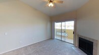 This single-floor residence offers a well-designed layout that balances comfort and functionality. The living room serves as the heart of the space, highlighted by vaulted ceilings, a ceiling fan with light fixture, and a tile-surround fireplace that adds warmth and character. Sliding glass doors open directly to a balcony, allowing natural light to fill the room and providing outdoor views. Plush carpeting runs throughout the living areas and bedrooms, creating a soft, comfortable underfoot experience.

The kitchen is efficiently arranged with white cabinetry, dark granite-style countertops, and stainless steel appliances including a refrigerator, electric range, and over-the-range microwave. Dark hardwood-style flooring anchors the kitchen and dining areas, which connect seamlessly via an open passageway featuring an arched architectural detail and a peninsula with bar seating.

The bedrooms continue the vaulted ceiling aesthetic and are carpeted for comfort. One bedroom includes a spacious walk-in closet with built-in shelving. The bathroom is clean and straightforward, featuring white cabinetry, granite-style countertops, a tiled tub-shower combination, and dark hardwood-style flooring. Overall, the space presents a bright, neutral palette throughout, making it versatile and move-in ready.