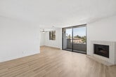 Located at 7017 Woodley Ave in Van Nuys, Los Angeles, this 2-bedroom, 3-bathroom home offers a thoughtfully designed single-floor layout with a clean, modern aesthetic throughout. Light wood laminate flooring flows seamlessly across all rooms, complemented by crisp white walls and abundant natural light from multiple windows fitted with horizontal blinds.

The open kitchen is a standout feature, equipped with stainless steel appliances including a gas range, built-in microwave, and dishwasher. White shaker-style cabinetry pairs with taupe countertops and a peninsula with a sink, creating a functional and stylish space for cooking and entertaining.

The living room is bright and airy, highlighted by floor-to-ceiling sliding glass doors that open to a private balcony with outdoor views of mature trees. A classic brick fireplace adds a warm, inviting focal point to the space.

Both bedrooms are well-proportioned and filled with natural light. The primary bedroom features mirrored sliding closet doors, while the second bedroom includes large windows offering pleasant outdoor views. A textured ceiling detail is present throughout.

The three bathrooms are finished consistently with white cabinetry, taupe countertops, and clean tile work. One bathroom features a full soaking tub with an overhead shower, while the others offer vanity and toilet configurations ideal for everyday use.