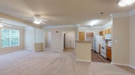 Located at 8400 Brass Mill Ln in Raleigh, NC, this single-floor residence offers a well-organized layout designed for comfortable everyday living. The open-concept living and dining area serves as the heart of the home, featuring neutral-toned carpet, crown molding, decorative columns, and a ceiling fan that enhances airflow and ambiance. Large windows allow natural light to fill the space, offering views of the surrounding greenery.

The galley-style kitchen is efficiently designed with warm wood-toned cabinetry, a double-basin sink, laminate countertops, a full suite of white appliances including a refrigerator, electric range, and dishwasher, and a dedicated wine rack built into the upper cabinetry. Wood-look flooring runs throughout the kitchen, adding a polished contrast to the carpeted living areas.

The bedrooms are generously sized, each equipped with ceiling fans, soft carpeting, and access to closet space, including a walk-in closet in one of the rooms. Natural light filters in through large windows with views of mature trees outside.

The bathroom features warm wood-toned cabinetry with ample storage, a wide vanity mirror with overhead lighting, a full soaking tub with tiled surround, and wood-look flooring that ties the space together. Overall, the residence presents a cohesive, neutral palette throughout.