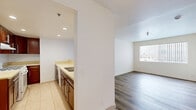 Located at 924 S Carondelet St in Los Angeles, CA, this two-bedroom, one-bathroom unit offers a practical and well-appointed single-floor layout. The combined kitchen and living area forms the heart of the home, where the kitchen stands out with rich dark wood cabinetry, light countertops, recessed lighting, and a gas range. A peninsula-style counter separates the kitchen from the living area, creating an open and connected feel. The living room features hardwood-style flooring and a large window with vertical blinds that allows natural light to fill the space.

Both bedrooms are carpeted, providing a warm and comfortable atmosphere. The primary bedroom is generously sized and offers direct access to the shared bathroom, which is finished with large-format tile flooring, matching wood cabinetry, a wide vanity with a light countertop, a wall mirror, and a full shower-tub combination. The second bedroom also features carpet and bright white walls, contributing to a clean and neutral aesthetic throughout.

The unit's overall design is clean and functional, with white walls and consistent finishes tying each room together cohesively. Situated in the vibrant community of Los Angeles, this unit provides a comfortable urban living experience.