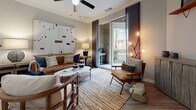 This single-floor residence offers a thoughtfully designed layout that balances functionality with modern style. The open-concept kitchen is a standout feature, showcasing rich dark-wood cabinetry, granite countertops, a subway tile backsplash, and stainless steel appliances including a gas range and built-in microwave. A central island with bar seating and pendant lighting serves as both a workspace and casual dining area, while wood-look flooring extends throughout the main living spaces.

The living room is generously proportioned, featuring crown molding, a ceiling fan, and floor-to-ceiling sliding glass doors that flood the space with natural light and open onto a private balcony with outdoor seating. The balcony provides views of surrounding greenery, adding a welcoming, open-air element to the home.

Two bedrooms are finished with plush carpeting. The primary bedroom connects to a walk-in closet with built-in shelving and rack systems. Both bathrooms feature white shaker-style cabinetry, large-format tile flooring, and well-lit vanity mirrors. One bathroom includes a navy accent wall and white countertops, while the second offers a full tub-shower combination in a neutral gray palette.