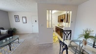 Located at 865 Revere Village Ct in Dayton, Ohio, this single-floor residence offers a well-organized layout designed for comfortable everyday living. The living room is a welcoming, light-filled space with neutral gray walls, plush carpeting, and a window dressed with sheer curtains that allow natural light to filter in. An adjacent dining area is anchored by a ceiling fan with a light fixture, providing a functional space for meals just steps from the kitchen. The kitchen is a galley-style space featuring rich dark wood cabinetry, a double-basin stainless steel sink, light countertops, and tile flooring. A decorative Eiffel Tower wall mural adds a distinctive and playful character to the room. A half-wall with decorative spindle columns creates an open visual connection between the kitchen and dining areas. The two bedrooms are carpeted, bathed in natural light through curtained windows, and offer ample space for rest and storage. The full bathroom includes a white vanity with cabinet storage, tile flooring, and a shower-tub combination. Throughout the home, textured ceilings and a consistent neutral color palette create a cohesive and understated ambiance.
