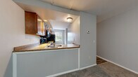 Located at 34 N Shore Cir in Rochester, NY, this multi-floor home spans three levels and offers a practical, well-organized layout with two bedrooms and two full bathrooms. The entry level welcomes you with a closet conveniently positioned near the front door, leading into the main living areas. The open-concept kitchen and dining area features warm wood cabinetry, granite-look countertops, a peninsula with a built-in sink, and black appliances, all opening toward a naturally lit dining space with a window view. The living room provides a comfortable, carpeted gathering space with neutral gray walls that carry throughout the home. Both bedrooms are carpeted and finished with the same soft gray tones, each benefiting from natural light through windows with outdoor views. The bathrooms include wood-vanity cabinetry, white countertops, wood-look vinyl flooring, and tub-shower combinations with bright overhead lighting. Multiple closets across the floors provide ample storage. The unfinished basement offers generous additional space with a concrete floor, exposed ceiling joists, utility systems including a water heater, and staircase access — ideal for storage or future finishing. The home's multi-floor design is connected by several staircases, ensuring easy navigation throughout.