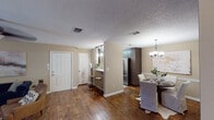 This single-floor residence offers a thoughtfully designed open-concept layout that seamlessly connects its key living areas. Rich hardwood flooring flows throughout the main living spaces, anchoring the warm, neutral color palette that defines the home's overall aesthetic.

The kitchen is a functional highlight, featuring dark cabinetry, light stone-look countertops, a double stainless steel sink, pendant lighting, and a stainless steel refrigerator. A peninsula with a breakfast bar connects the kitchen to the dining area, which is illuminated by an elegant chandelier and offers a welcoming space for seated meals.

The living room is bright and comfortable, centered around French doors that invite natural light. A ceiling fan adds practicality, while the layout provides ample room for relaxed entertaining.

The bedrooms are carpeted and cozy, each equipped with ceiling fan lighting and closet space. The primary bedroom is generously proportioned, offering a peaceful retreat.

The bathroom continues the home's cohesive design with light cabinetry, a stone-look vanity countertop, hardwood-style flooring, and a full tub-shower combination. Textured ceilings are present throughout, adding a consistent architectural detail across all rooms.