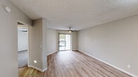 Located at 1440 S Val Vista Dr in Mesa, AZ, this 1-bedroom, 1-bathroom unit offers a well-organized, single-floor layout designed for comfortable everyday living. Light wood-style flooring flows throughout the main living areas, complementing the neutral warm-beige walls and white trim that give the space a clean, cohesive aesthetic.

The living room is bright and open, featuring a ceiling fan, a textured ceiling, and a sliding glass door with vertical blinds that leads to a private balcony overlooking lush outdoor greenery. The adjacent bedroom is a comfortable size, carpeted for warmth, and includes built-in wall shelving and its own sliding glass door access to the balcony, flooding the room with natural light.

The galley-style kitchen is well-appointed with crisp white shaker cabinetry, black hardware accents, white quartz countertops, a stainless steel sink, and a full suite of stainless steel appliances including a refrigerator, range, and microwave. A skylight-style ceiling fixture adds brightness to the space. Open shelving at the end of the kitchen provides additional storage.

The bathroom features a white vanity with quartz countertop, a tub-shower combination, and wood-style flooring that ties back to the rest of the unit. A hallway connects the rooms, completing this efficiently designed and thoughtfully updated home.