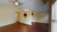 Located at 2330 W Jefferson St in Louisville, KY, this single-story unit offers a well-organized layout with a mix of practical finishes and notable architectural details throughout. The open living and dining area serves as the heart of the home, showcasing vaulted ceilings that lend a sense of spaciousness and volume. Rich, dark hardwood-style flooring runs throughout these main areas, complemented by warm yellow-toned walls that create a bright, welcoming ambiance. A ceiling fan with a light fixture provides both comfort and illumination, while a pendant light adds a stylistic accent overhead. Large windows dressed with horizontal blinds allow generous natural light to fill the living space, offering views of the surrounding neighborhood.

The kitchen is efficiently designed with warm wood cabinetry extending to the upper walls, white laminate countertops, and a full suite of white appliances including an electric range, dishwasher, and refrigerator. A pass-through window connects the kitchen to the main living area, enhancing the open feel of the floor plan.

The bedrooms feature plush carpeting and are well-lit by windows with blinds. One bedroom benefits from vaulted ceilings and a ceiling fan. The bathroom includes a full tub and shower combination with clean white surrounds and chrome fixtures.