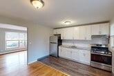Located at 22 Revere Dr in Bloomfield, CT, this 2-bedroom, 1-bathroom unit offers a practical and comfortable single-floor layout. Warm hardwood flooring flows throughout the living areas and bedrooms, lending a cohesive and inviting feel to the space. The living room is bright and open, with a large window that fills the room with natural light and provides views of the surrounding landscape. A wood-paneled entry door adds a touch of character to the welcoming space.

The kitchen is well-equipped and thoughtfully updated, featuring crisp white cabinetry, granite-style countertops, stainless steel appliances including a refrigerator, gas range, and under-cabinet range hood, as well as a stainless steel sink. Dark hardwood flooring in the kitchen provides a clean contrast to the light wood in the adjacent living area.

Both bedrooms continue the hardwood flooring theme, painted in neutral gray tones. The primary bedroom is generously sized and includes a built-in closet with paneled doors. The second bedroom benefits from a window with natural light and a baseboard heating unit. The bathroom is neatly finished with large-format tile flooring, a tiled tub-shower surround with a dark stone-look tile accent, and a window for ventilation. A hallway connects the main living spaces efficiently.