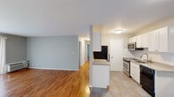 This single-floor unit offers a thoughtfully designed layout that balances open communal spaces with comfortable private areas. The living room is generously proportioned, featuring warm hardwood flooring, soft gray walls, and a large sliding glass door dressed with vertical blinds that allows natural light to fill the space. A wall-mounted HVAC unit ensures year-round climate control.

The kitchen is open to the living area and separated by a half-wall peninsula with a light granite countertop, creating a natural pass-through ideal for casual dining or entertaining. The kitchen is equipped with stainless steel appliances, including a GE electric range with a smooth cooktop, an over-the-range microwave, and a black dishwasher. White cabinetry and a white subway tile backsplash complement the light tile flooring, while a stainless steel sink with a pull-down faucet adds a modern touch.

The bedrooms continue the hardwood flooring theme and are painted in the same calming gray palette. Each room includes a window with blinds for natural light and privacy, a wall HVAC unit, and an open closet with wire shelving for organized storage.

The bathroom features full-surround beige tile walls enclosing a soaking tub with an overhead shower. Throughout the unit, clean white trim and neutral tones create a cohesive and move-in ready atmosphere.