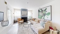 Located at 601 Cabot Ct in Woodbury, New Jersey, this single-floor residence offers a thoughtfully designed open-concept layout with light wood-style flooring flowing throughout the main living areas. The spacious living room is a standout feature, anchored by a classic fireplace framed in a soft blue surround, flanked by windows that invite natural light. A floating white media console provides a sleek, modern focal point, complemented by a generous sectional seating area.

The adjoining dining area transitions seamlessly into the kitchen, which is equipped with white shaker cabinetry, stainless steel appliances including a gas range, refrigerator, and dishwasher, as well as dark countertops and a breakfast bar for casual dining.

The bedrooms are carpeted for comfort, each offering closet storage and windows with blinds and sheer curtains that allow for natural light. The bathroom features a glass-enclosed shower stall, a vanity with a clean white finish, and light wood-style tile flooring.

A dedicated in-unit laundry room houses a full-size washer and dryer, adding everyday convenience. The overall design aesthetic is clean and contemporary, with neutral tones throughout that create a bright, welcoming ambiance across every room.