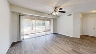 Located at Park Village Way in Melbourne, Florida, this well-appointed 2-bedroom, 2-bathroom residence offers a comfortable and functional single-floor layout. Wood-style plank flooring flows consistently throughout the home, complemented by a neutral color palette and textured ceilings that lend warmth to every room.

The combined dining room, kitchen, and living area forms the heart of the home. The living room is bright and airy, featuring a ceiling fan with light fixture and sliding glass doors that open to a private balcony, inviting natural light and outdoor views. A peninsula-style breakfast bar connects the kitchen to the main living space, making the layout ideal for everyday living and entertaining. The galley kitchen is equipped with white cabinetry, a range, refrigerator, dishwasher, and ample counter space, with a pantry providing additional storage.

Both bedrooms are generously sized, each featuring wood-style flooring, large windows with outdoor views, and dedicated closet space — three closets are distributed throughout the home. The primary bedroom is notably spacious and includes its own full bathroom with a wide vanity and walk-in shower. The second bathroom features a full tub-shower combination and a bright vanity mirror. Additional conveniences include a dedicated laundry area and a hallway connecting the private quarters of the home.