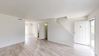 Located at 2320 Canterwood Dr in Wilmington, NC, this two-story home offers four bedrooms and two full bathrooms across two evenly divided floors. The main level features light-toned luxury vinyl plank flooring throughout the living and dining areas, creating a clean, cohesive aesthetic. Two connected living spaces provide flexible room for entertaining or everyday use, with a ceiling fan and natural light visible toward the front of the home. A staircase with white railing leads to the upper floor. The kitchen is outfitted with white cabinetry, dark countertops, and stainless steel appliances including a refrigerator, dishwasher, and range. The bathrooms feature light wood-look flooring, gray countertop vanities, white cabinetry, and a tiled tub-shower combo. Bedrooms are carpeted in a neutral tone, offering a comfortable feel, with windows providing natural light and views of the surrounding neighborhood. Additional bedrooms on the main floor feature the same light vinyl plank flooring. Neutral, warm-white walls throughout the home create a bright and move-in-ready atmosphere. A hallway connects key areas on each floor, adding to the home's practical layout.