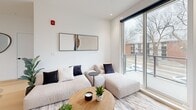 Located in Edmonton's desirable Oliver neighbourhood, this thoughtfully designed 2-bedroom, 3-bathroom unit offers a clean, modern aesthetic throughout its single-floor layout. Light hardwood flooring flows seamlessly across all living areas, complementing the bright white walls and creating a cohesive, contemporary feel.

The open-concept living, dining, and kitchen area serves as the heart of the unit. The kitchen is well-appointed with warm wood lower cabinetry, crisp white upper cabinets, white quartz countertops, and stainless steel appliances including a built-in range, over-the-range microwave, and French door refrigerator. A kitchen island provides additional prep and seating space. The living area is bathed in natural light from large sliding glass doors that open onto a private balcony with views of the surrounding neighbourhood.

The primary bedroom features corner windows that invite abundant natural light and offer outdoor views, with a dedicated walk-in closet and private ensuite access. The second bedroom is equally well-lit with a large window. Floating wood shelves in one bedroom add functional character. All three bathrooms maintain a consistent minimalist design with white tile, wood vanity cabinetry, and clean fixtures. Additional conveniences include in-unit laundry, a utility room, and ample closet storage.