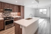 Located at 17600 Cartwright Rd in Irvine, California, this single-floor residence showcases a clean, contemporary design with an emphasis on functionality and modern aesthetics. The open-concept kitchen serves as the heart of the home, featuring rich walnut-toned cabinetry, a mosaic tile backsplash, stainless steel appliances including a gas range, built-in microwave, and refrigerator, and a generous island with a white quartz countertop and undermount sink — ideal for both cooking and casual dining. Pendant lighting adds a warm, refined touch above the island and throughout the living area. The living space is bathed in natural light from large windows that offer views of the surrounding community, and is finished with light wood-tone flooring that runs seamlessly throughout the unit. The bedroom is a bright, calm retreat with its own window, clean white walls, and durable wood-look flooring. The bathroom is well-appointed with a dual-sink vanity, white quartz countertops, a linear tile backsplash, a full-width mirror, and a glass-enclosed shower. Recessed lighting and a neutral color palette tie all areas together, creating a cohesive, inviting atmosphere throughout this thoughtfully designed Irvine residence.