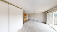 Located at 1800 S 330th St in Federal Way, Washington, this efficiently designed studio unit offers a well-organized layout that makes the most of its compact footprint. The living area is finished with neutral-toned carpet and features clean white walls, a baseboard heater, and a sliding glass door that allows natural light to fill the space while providing access to an outdoor balcony with views of surrounding greenery.

The galley-style kitchen is thoughtfully arranged, featuring warm wood-trimmed upper cabinets with frosted panel inserts, laminate countertops, a sink, a full-size refrigerator, and an electric coil range — providing all essential cooking amenities within an efficient corridor layout. Light wood-style flooring runs through the kitchen and connects to the rest of the unit.

The bedroom area is carpeted and includes a sliding-door closet offering built-in storage, complemented by a window that brings in additional natural light.

The bathroom is equipped with a single-sink vanity featuring wood-trimmed cabinetry and a speckled countertop, a wall-mounted mirror with overhead lighting, a toilet, and a tub-shower combination. An electrical panel is conveniently accessible just outside the bathroom. The unit's clean, neutral palette and functional design make it a practical and comfortable living space.