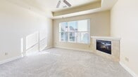 Located in Colorado Springs, CO, this well-appointed 2-bedroom, 2-bathroom residence offers a thoughtfully designed single-level layout. The open-concept kitchen and living area serves as the heart of the home, featuring rich dark-cabinetry, granite countertops, a central island with pendant lighting, and black appliances including a stainless steel refrigerator. Track lighting and hardwood-style flooring complete the kitchen's polished look. The living room flows seamlessly from the kitchen, highlighted by a tile-surround fireplace, a tray ceiling with a ceiling fan, large windows that invite abundant natural light, and sliding glass door access to a private balcony. Both bedrooms are generously proportioned and finished with plush carpet and large windows that bathe the rooms in sunlight. The primary bedroom includes a ceiling fan for added comfort. The two bathrooms are finished with dark wood vanities and white countertops; one features a shower/tub combination, while the other offers a walk-in shower area. A dedicated laundry room houses a full-size washer and dryer alongside a water heater. Throughout the residence, warm neutral tones and clean architectural lines create a bright, cohesive ambiance.