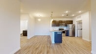 This thoughtfully designed 2-bedroom, 2-bathroom residence offers a comfortable and functional single-floor layout. The open-concept kitchen and living area serves as the heart of the home, featuring light wood-style flooring, recessed lighting, and stylish pendant lights that illuminate the central kitchen island with granite countertops and a built-in sink. The kitchen is equipped with stainless steel appliances—including a refrigerator, electric range, microwave, and dishwasher—complemented by rich dark cabinetry and a white subway tile backsplash. The spacious living area flows seamlessly from the kitchen, bathed in natural light.

The primary bedroom is generously sized and includes sliding glass doors that open to a private balcony offering expansive outdoor views of the surrounding landscape. Both bedrooms feature plush carpeting and dedicated closets with built-in shelving and hanging rods. The bathrooms are well-finished, showcasing granite-topped vanities with dark wood cabinetry, large mirrors, and tiled tub-shower combinations with light wood-style flooring. A dedicated in-unit laundry room with built-in shelving adds everyday convenience. Throughout, the residence maintains a clean, modern aesthetic with neutral tones and quality finishes.