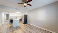 This efficiently designed 2-bedroom, 1-bathroom unit offers a practical single-floor layout that makes smart use of its available space. The combined kitchen and living area serves as the heart of the unit, featuring light wood-style flooring and a ceiling fan with built-in lighting. The kitchen is well-appointed with crisp white shaker cabinetry, stainless steel appliances including a refrigerator, electric range, microwave, and dishwasher, along with an in-unit washer. A peninsula counter provides additional prep space and separates the kitchen from the living area. The living room benefits from natural light through a window fitted with blinds and includes a front entry door. The spacious primary bedroom is finished with plush carpeting, a ceiling fan, and a double-door closet. The second bedroom features light wood-style flooring, a large window with blinds that brings in natural light, and neutral-toned walls. A utility area with a water heater is also present. The shared bathroom offers a full tub-shower combo, a white vanity with storage, and matching wood-style flooring, finished with brushed nickel fixtures throughout. Neutral wall tones and clean white trim tie the entire unit together with a cohesive, move-in-ready aesthetic.