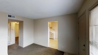 This single-floor home features three bedrooms and one and a half bathrooms, offering a well-organized layout suited for a variety of living arrangements. The living area is finished with wall-to-wall carpeting and neutral-toned walls that create a calm, versatile backdrop for furnishing and décor. A textured ceiling adds a classic touch throughout the main living space. An open doorway connects the living room directly to the kitchen, promoting an easy flow between the two areas. The kitchen is outfitted with white cabinetry providing ample storage, a sink with under-cabinet space, and light-toned flooring that contrasts with the carpeted living areas. The overall color palette throughout the home is light and understated, contributing to a bright and airy feel. The straightforward, single-level floor plan ensures accessibility and ease of navigation between rooms. With three dedicated bedrooms, the home accommodates families, roommates, or those in need of additional space for a home office or guest room. The 1.5 bathrooms offer added convenience for daily routines. Overall, this residence presents a functional and move-in ready living environment with a clean, no-frills design.
