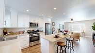 Located at 35995 Fremont Blvd in Fremont, California, this well-designed one-bedroom, one-bathroom unit offers a thoughtfully organized single-floor layout that maximizes every square foot. The open-concept kitchen and living area form the heart of the home, with the kitchen showcasing crisp white shaker cabinetry, light granite-style countertops, a full suite of stainless steel appliances including a gas range, built-in microwave, dishwasher, and refrigerator, and a central island with bar seating — ideal for casual dining or entertaining. Recessed lighting brightens the space, complemented by warm hardwood-style flooring that flows throughout. The adjoining living room is bathed in natural light through large windows fitted with horizontal blinds, creating a bright and welcoming atmosphere. A ceiling fan adds comfort overhead. The bedroom offers a cozy retreat with plush carpeting, a ceiling fan, warm neutral walls, and access to an outdoor area through sliding glass doors. The full bathroom features a single-vanity with a stone-topped counter, a large mirror, and a shower-tub combination with a window above for natural ventilation. Clean finishes and a cohesive neutral palette tie the entire space together for a polished, move-in-ready feel.